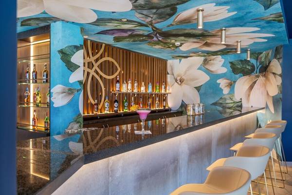 Innenansicht der Bar im Sentido Galosol Hotel mit blauer Wand, Blumenmalerei und weißen Stühlen.