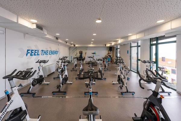 Fitnessstudio im Sentido Galosol Hotel mit vielen Spinrädern und einer Wand mit dem Text 'Feel the Energy'.