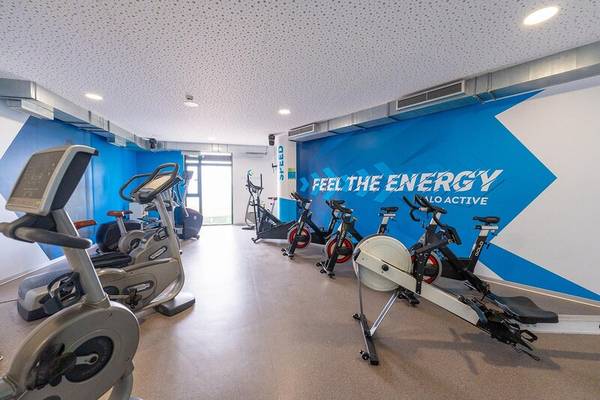 Fitnessstudio im Sentido Galosol Hotel mit modernen Cardiogeräten und einer blauen Wand mit dem Text 'Feel the Energy'.