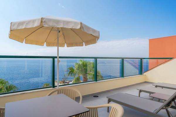 Terrasse im Hotel Sentido Galosol mit Blick auf das Meer, Sonnenschirm und Liegestühlen.