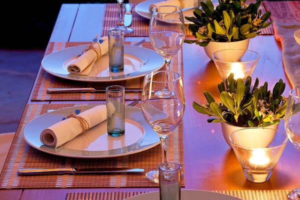 Gedeckter Esstisch im Yria Island Boutique Hotel & Spa mit Tellern, Gläsern und Kerzen.