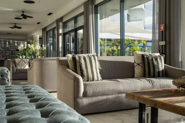 Lounge-Bereich des Baia Azul Hotels mit Sofas, Kissen und einem Tisch.