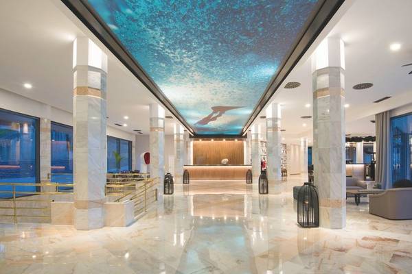 Empfangsbereich des Baia Azul Hotels mit moderner Innenarchitektur und einer blauen Deckenprojektion.