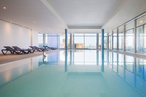 Innenpool des Baia Azul Hotels mit Sonnenliegen und Glaswänden