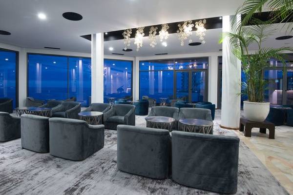 Lobby des Baia Azul Hotels mit großen Fenstern und modernen Möbeln.