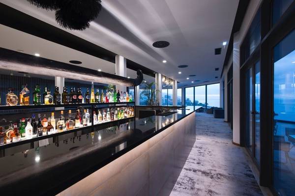 Cocktailbar im Baia Azul Hotel mit vielen Flaschen und großer Fensterfront.