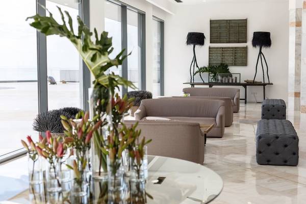 Lobby des Baia Azul Hotels mit Möbeln, Pflanzen und Aussicht auf das Meer.