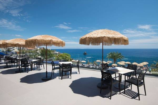 Außenterrasse des Baia Azul Hotels mit Blick auf das Meer und Palmen.