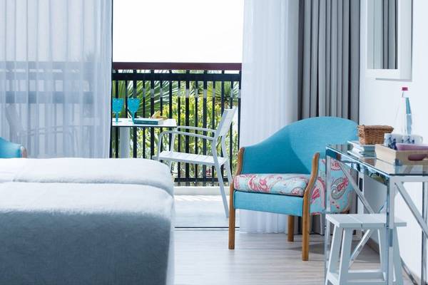 Schlafzimmer im Baia Azul Hotel mit Balkon, Bett, Stühlen und Tisch.