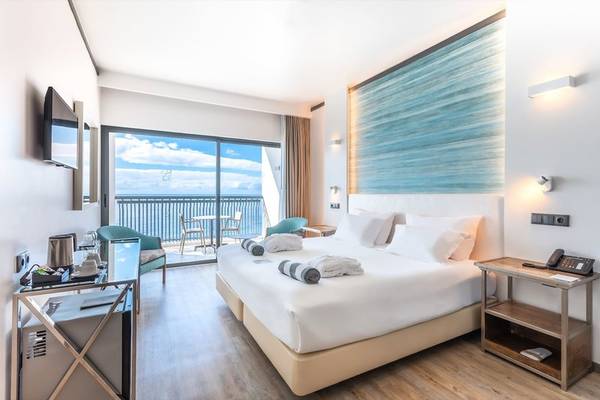 Ein modernes Hotelzimmer im Baia Azul Hotel mit Blick auf das Meer von einer Terrasse.
