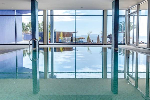 Innenpool des Baia Azul Hotels mit großer Glasfront und Meerblick