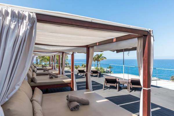 Terrasse des Saccharum Hotels mit mehreren Betten und Meerblick.