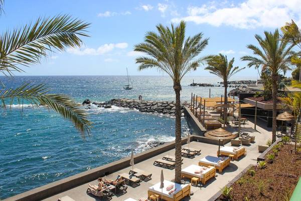 Saccharum Hotel Strandblick mit Liegestühlen und Palmen am Meer