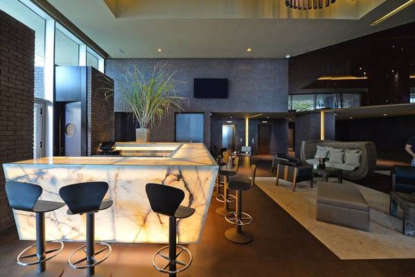 Lobby-Barbereich des Saccharum Hotels mit Marmortheke und modernen Stühlen.