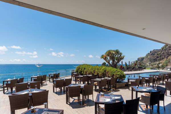 Terrasse des Saccharum Hotels mit Blick auf den Ozean und braunen Stühlen.