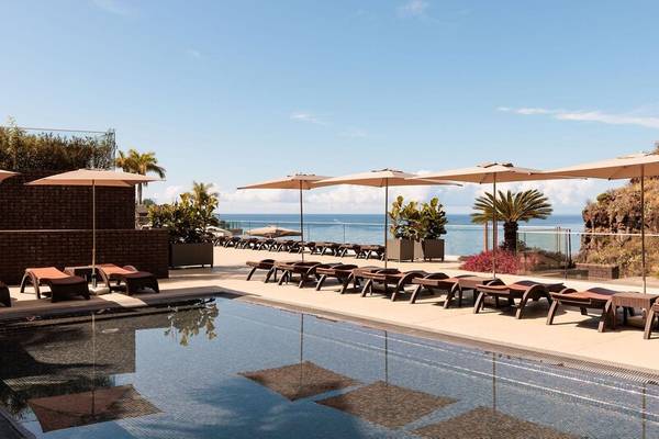 Pool-Terrasse des Saccharum Hotels mit Sonnenliegen und Pflanzen am Meer