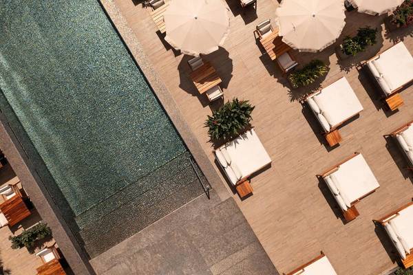 Luftaufnahme des Pools und der Terrasse des Saccharum Hotels mit Liegen und Sonnenschirmen.