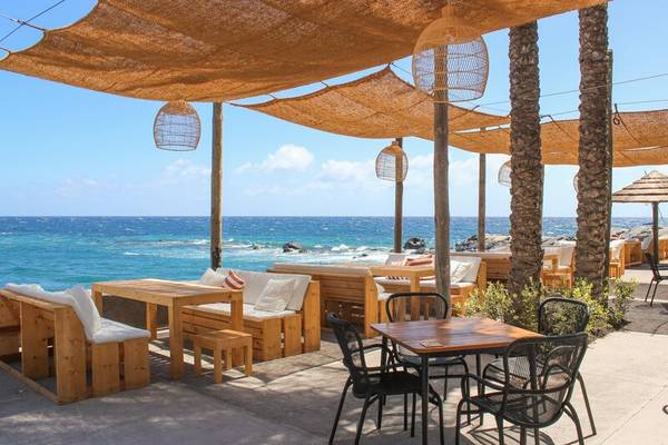 Außenterrasse des Saccharum Hotels mit Blick auf das Meer und holzgefertigten Möbeln.