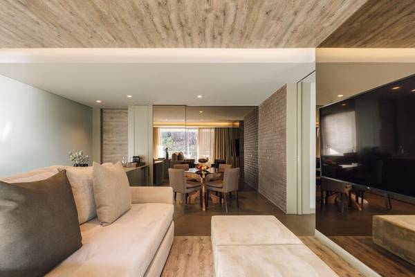 Wohnbereich des Saccharum Hotels mit Couch, Tisch, Fernseher und Holzboden.