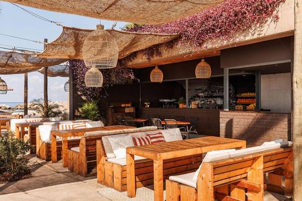 Terrasse des Saccharum Hotels mit Holztischen, Stühlen und Sonnenschirmen