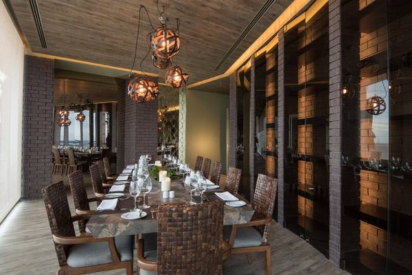 Innenansicht des Restaurants im Saccharum Hotel mit langen Tisch, Holzstühlen und modernen Kronleuchtern.