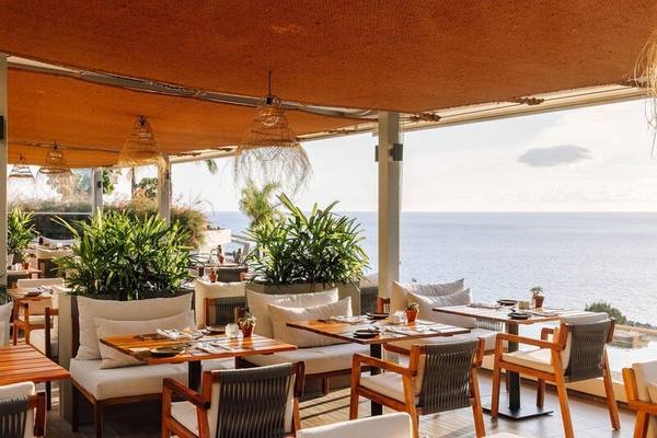 Terrasse des Saccharum Hotels mit Meerblick, Pflanzen und holztischen.