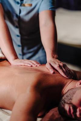 Eine Massage im Saccharum Hotel, bei der eine Person auf einem Bett liegt und von einer Masseurin massiert wird.