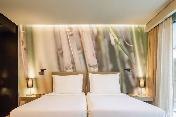 Doppelbett-Zimmer im Saccharum Hotel mit blumigem Wanddesign.