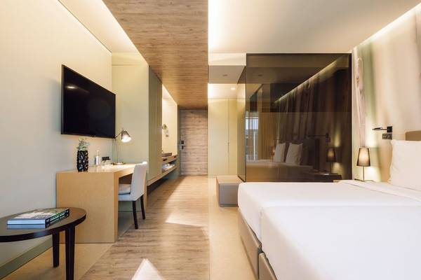 Innenansicht eines Doppelzimmers im Saccharum Hotel mit Schreibtisch, Fernseher, Betten und Einrichtung.