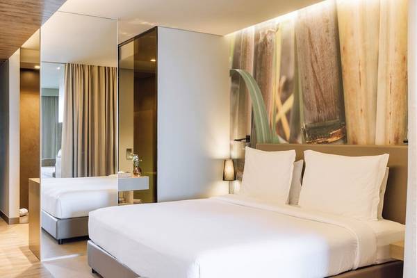 Ein modernes Schlafzimmer im Saccharum Hotel mit weißen Möbeln und einem großen Wandbild.