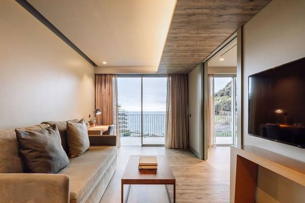 Wohnzimmer des Saccharum Hotels mit Meerblick, einem Sofa, einem Couchtisch und einem Fernseher.