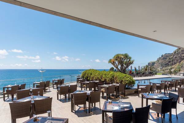 Außenterrasse des Saccharum Hotels mit Blick auf das Meer und einen Swimmingpool.