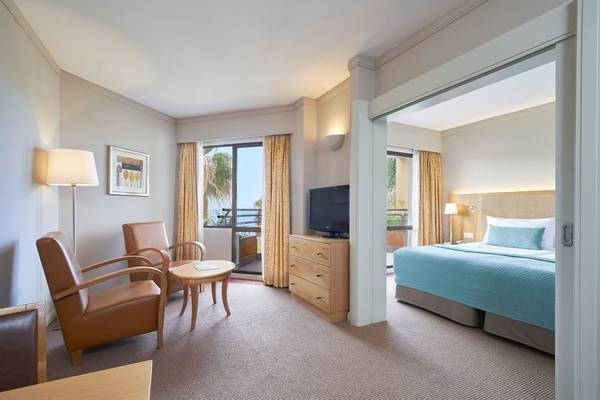 Suite Hotel Eden Mar Zimmer mit Blick auf das Meer, Bett, Fernseher, Tisch, Stühle und Lampe.