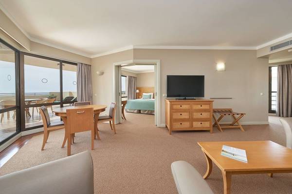 Innenraum des Suite Hotel Eden Mar mit Wohnzimmer, Esstisch und Fernseher.