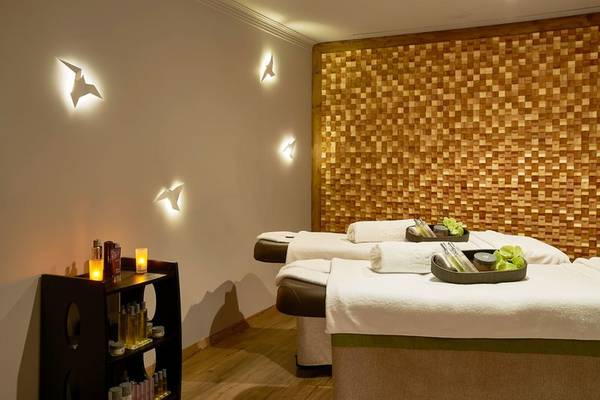 Spa-Behandlungsraum im Suite Hotel Eden Mar mit zwei Massagetischen, beleuchteten Wanddekorationen und einer kleinen Kommode.