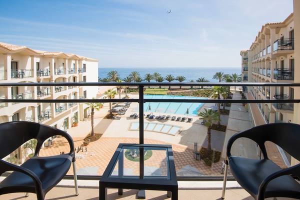 Blick vom Balkon auf das Meer beim Hotel Vila Galé Santa Cruz mit Swimmingpool und Gebäuden im Hintergrund.