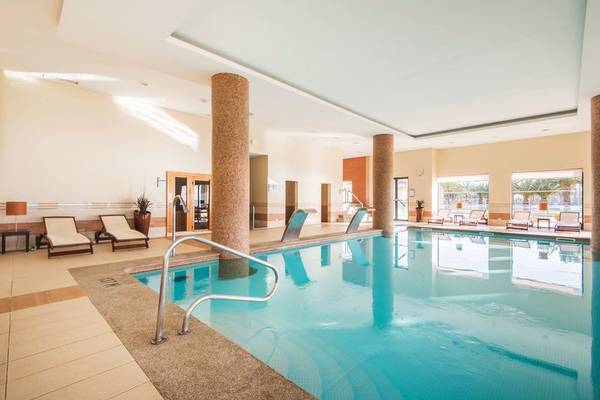 Innenpool des Vila Galé Santa Cruz Hotels mit Loungebereich und Treppen.