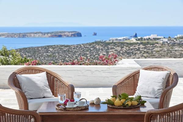Aussicht auf das Meer vom Hotelbalkon mit zwei Korbstühlen, einem Tisch und Obst.
