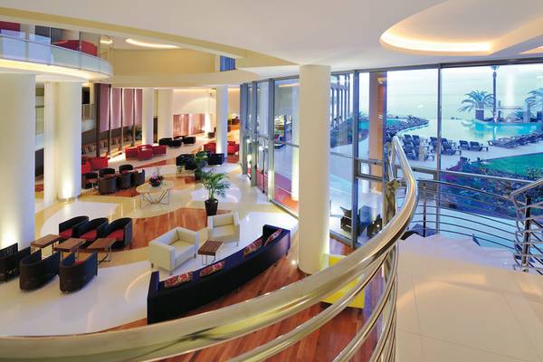 Innenansicht der Lobby des Pestana Promenade Hotels mit Sitzbereichen und Blick auf den Pool.