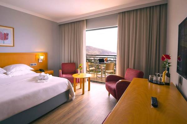 Hotelzimmer mit komfortablem Bett, Möbeln und Terrasse mit Blick auf den Berg