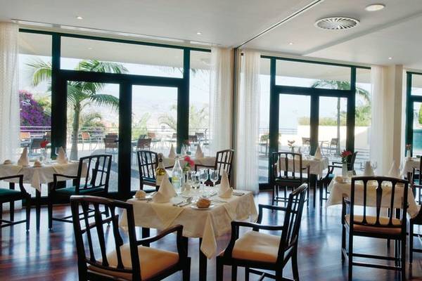Innenansicht des Restaurants im Madeira Panorâmico Hotel mit vielen gedeckten Tischen und Fenstern.