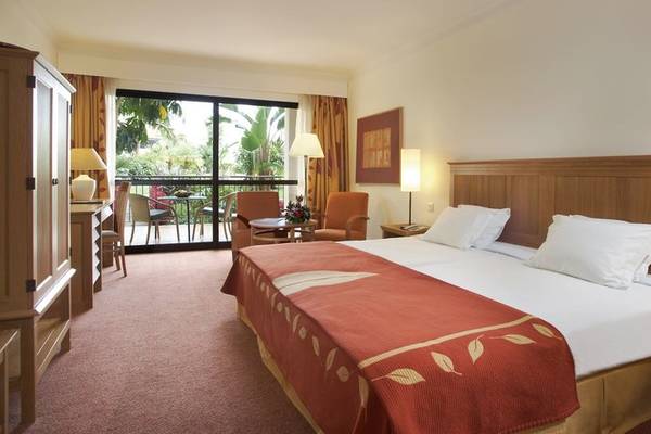 Ein Schlafzimmer im Hotel Porto Mare - PortoBay mit einem Doppelbett, einem Balkon und einem Wohnzimmerbereich.
