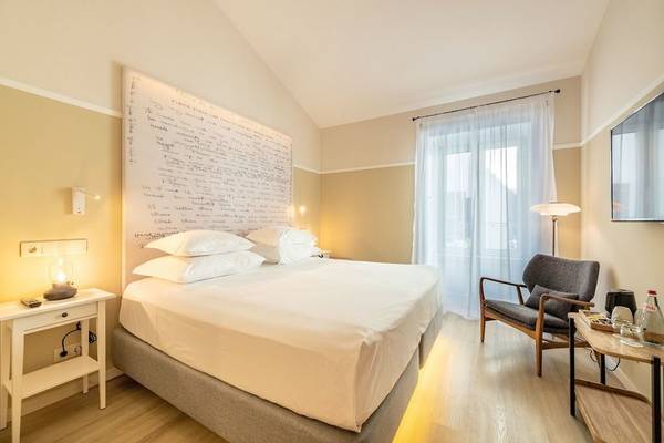 Schlafzimmer im Pestana Fisherman Village Boutique Hotel mit einem großen Bett, weißen Kissen, Nachttisch und Lampe.