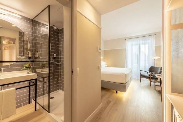 Innenansicht eines Zimmers im Pestana Fisherman Village Boutique Hotel mit Dusche, Bett und Wohnzimmerbereich.