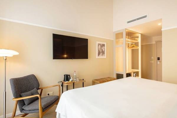 Innenansicht eines Zimmers im Pestana Fisherman Village Boutique Hotel mit Bett, Fernseher und Lampe.