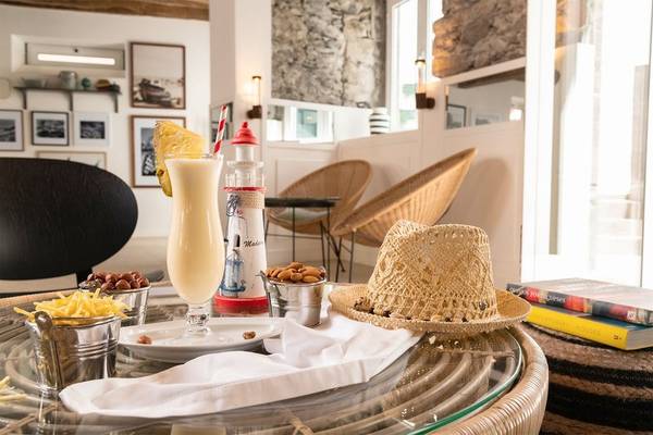Innenbereich des Pestana Fisherman Village Boutique Hotel mit einem Tisch, einem Glas mit einem Getränk, Snacks und einem Strohhut.