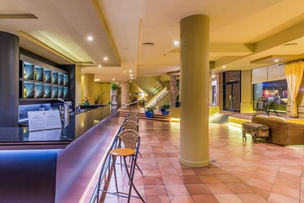 Innenbereich des Calheta Beach Hotel mit Bar, Stühlen, Säulen und Treppen.