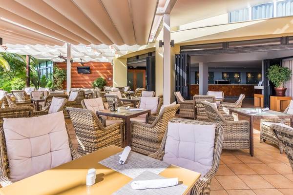 Terrasse des Calheta Beach Hotels mit Tischen und Stühlen, teilweise überdacht.