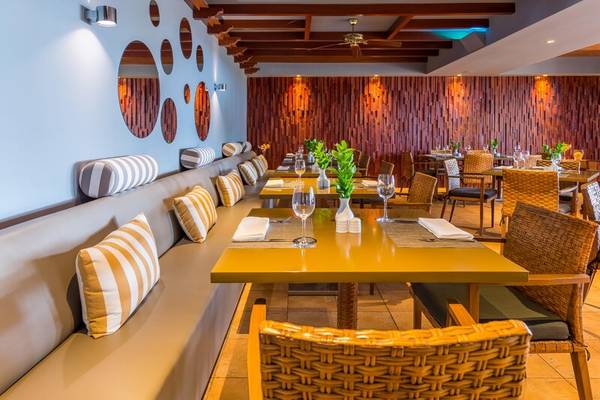 Innenraum des Restaurants des Calheta Beach Hotels mit gelben Tischen, braunen Stühlen und Holzwänden.