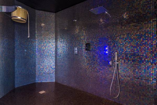 Dusche im Calheta Beach Hotel mit blauen Mosaikfliesen und blauer Beleuchtung.